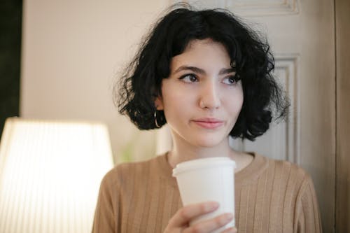 Woman in Brown Sweater Holding White Disposable Cup