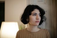 在灯光柔和的房间里，一位短发、戴鼻环的体贴女人凝视着远方