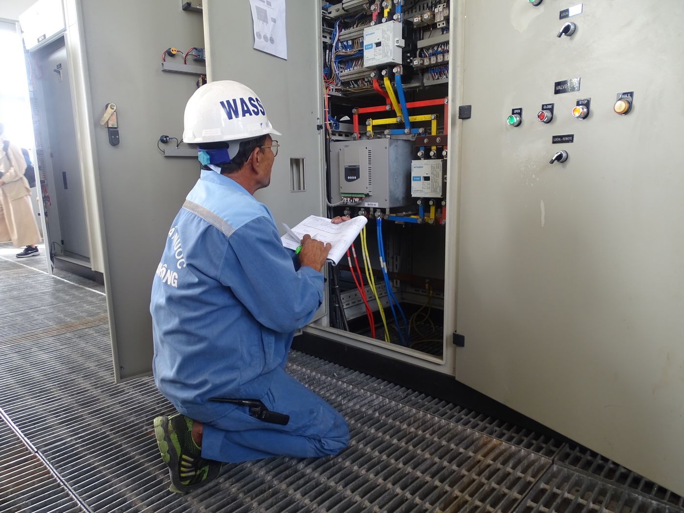 Engineer inspecting an industrial electrical control panel