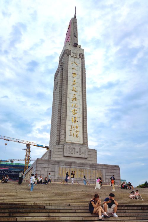 Free A towering monument with people on steps beneath a cloudy sky. Urban setting, cultural significance. Stock Photo