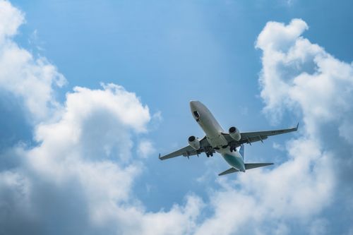 Free A commercial airplane soars in the sky with white clouds and blue backdrop, ideal for travel concepts. Stock Photo
