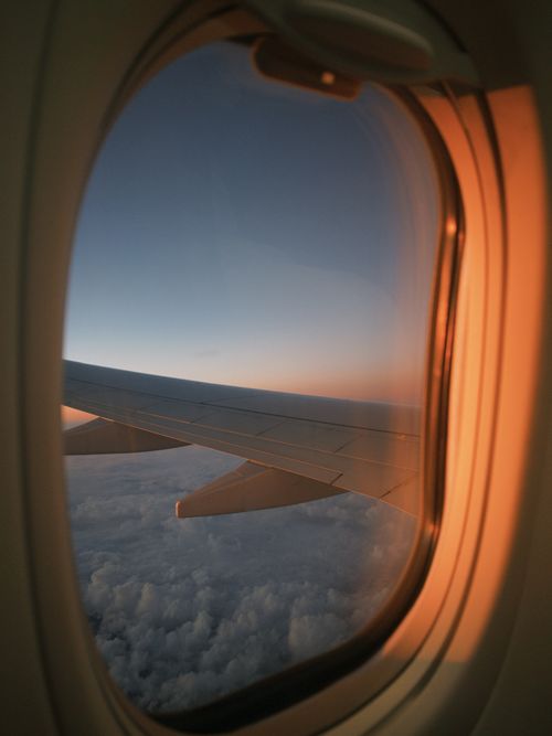 Free Scenic view from airplane window during sunset, highlighting the wing and sky over the clouds. Stock Photo