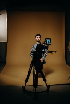 A model poses confidently in a professional studio with lighting and camera setup.