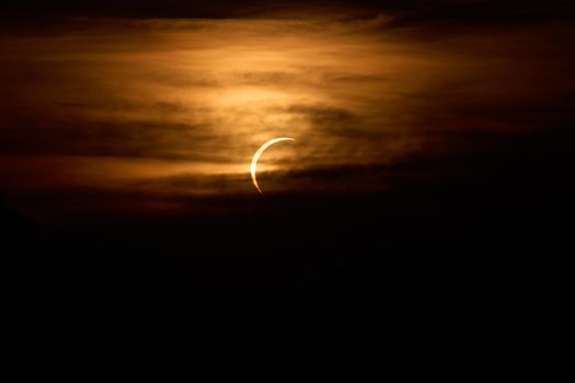A striking crescent moon illuminates the sky amidst dramatic clouds at twilight.