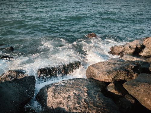 Free Serene view of waves hitting rocks on a beach during the day, showcasing nature's beauty. Stock Photo