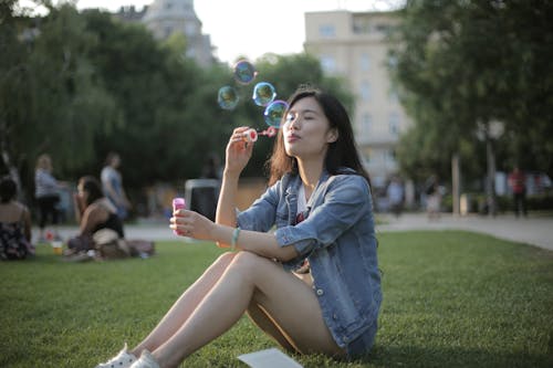 Woman in Blue Denim Jacket Sitting on Green Grass Field