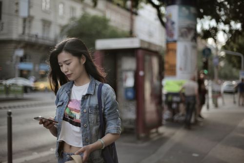 Free Casual urban walk with woman using smartphone outdoors on a sunny day. Stock Photo