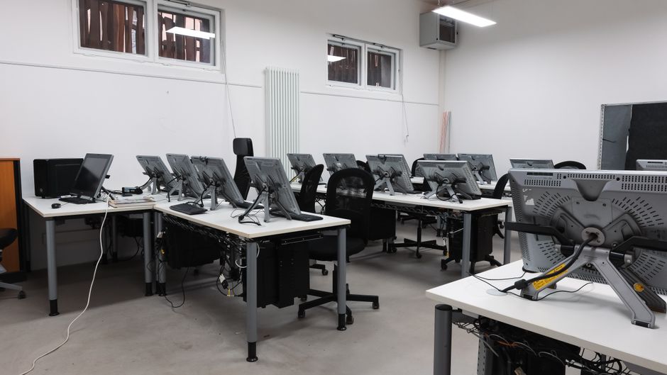 An empty computer lab featuring multiple vacant workstations with modern monitors.
