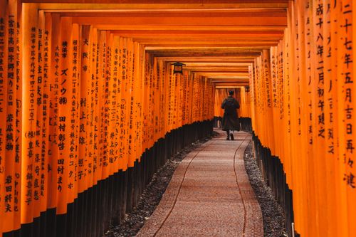 Free A person walking through the iconic torii gate pathway at Fushimi Inari Taisha in Kyoto, Japan. Stock Photo