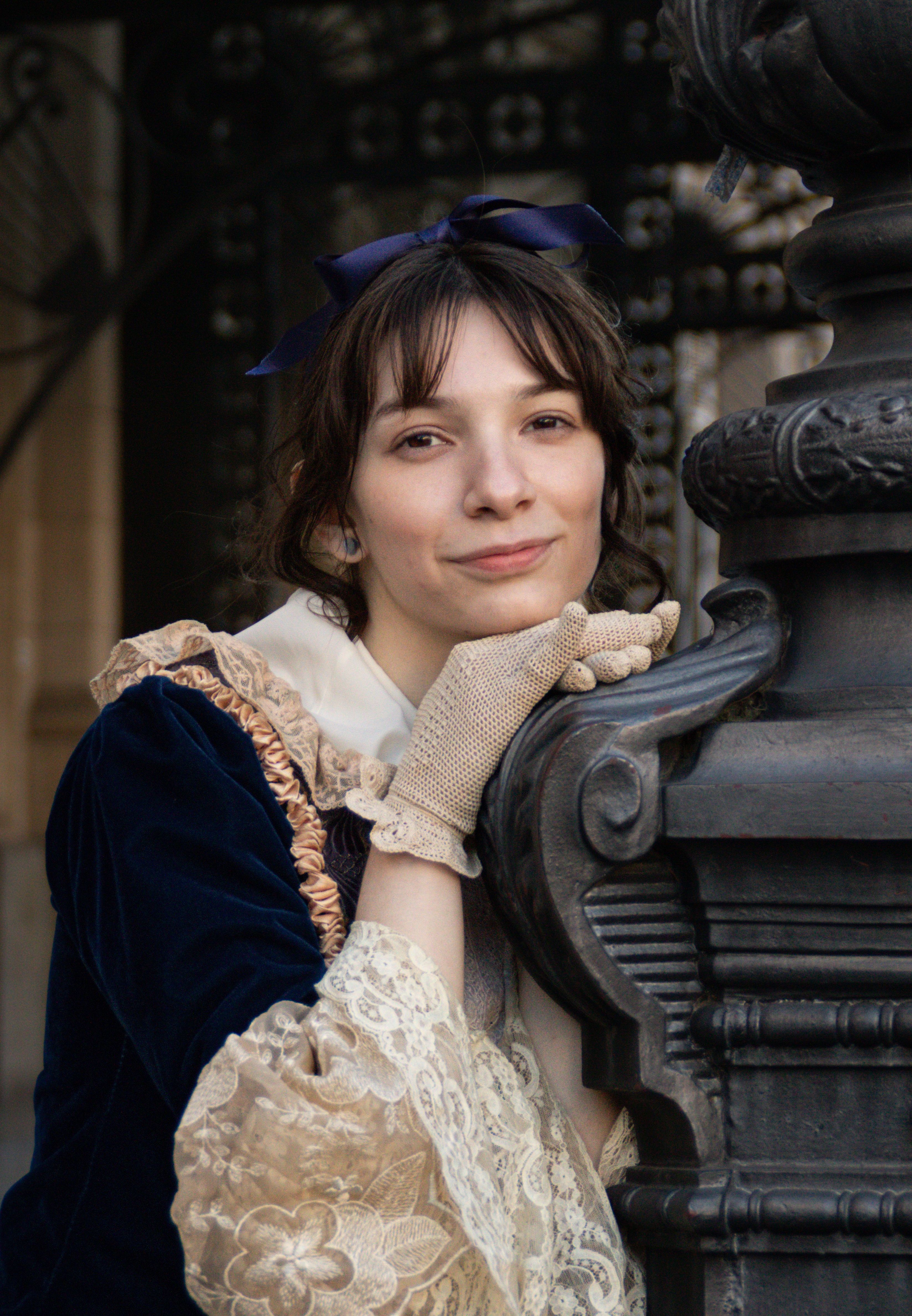 A woman in Victorian attire posing by ornate architecture in Buenos Aires.