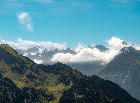 A breathtaking view of the Swiss Alps with rolling green hills and dramatic clouds.