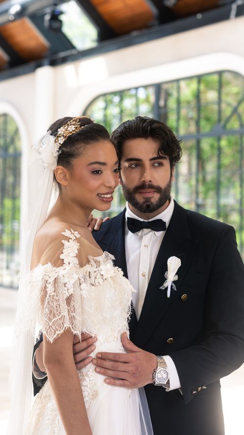 Free A joyful wedding couple poses in an elegant, sunlit indoor venue, showcasing love and style. Stock Photo