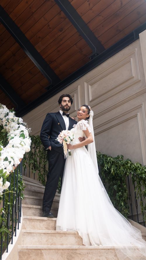 Free Beautiful wedding couple posing on indoor staircase with floral decor. Stock Photo