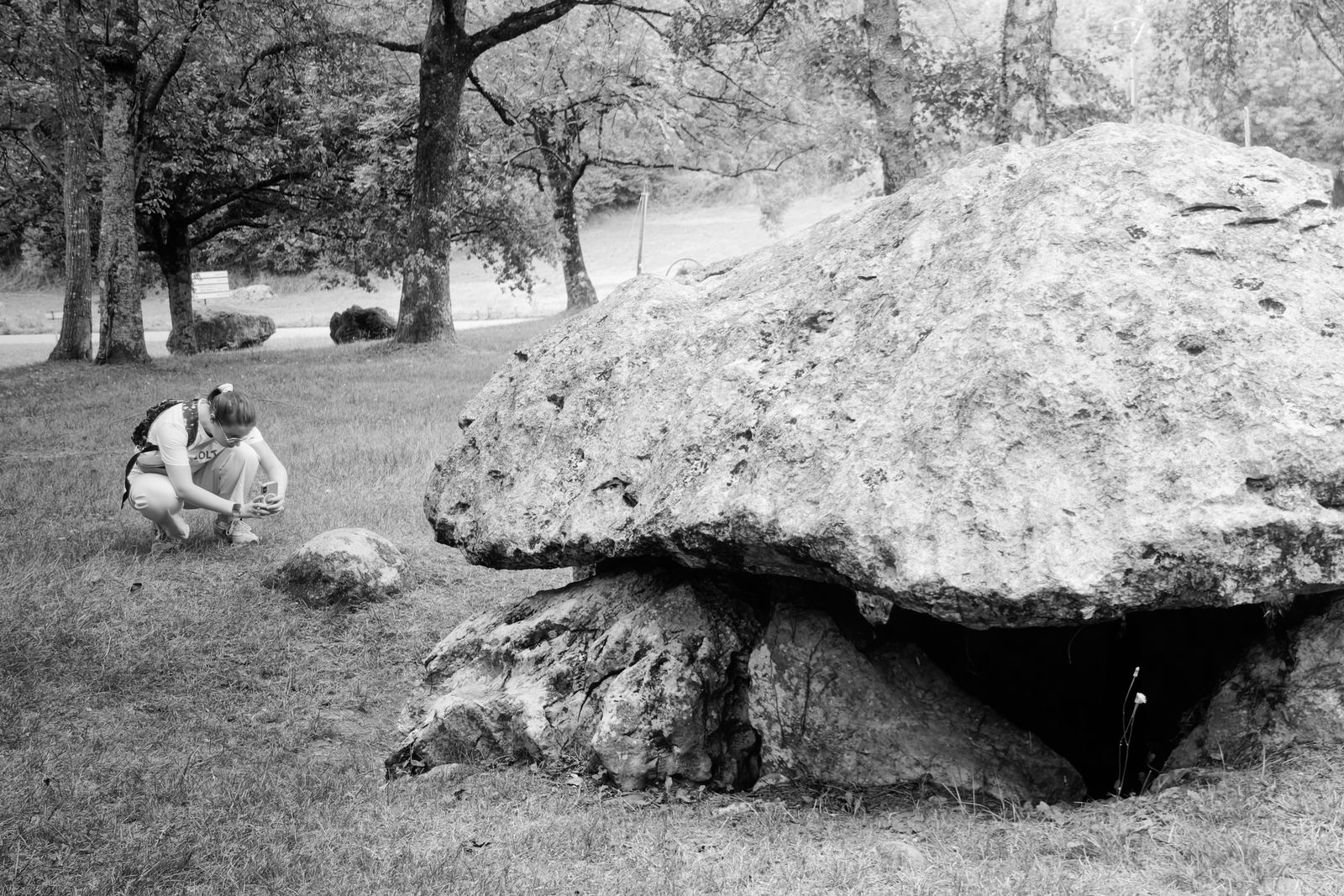 Un visiteur observe un dolmen préhistorique près de Pau, en noir et blanc