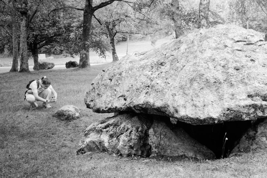 A visitor examines an ancient dolmen near Pau in black and white