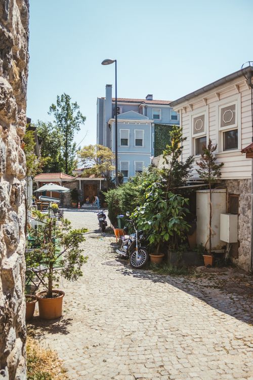Free Cobblestone street lined with quaint houses and potted plants under a clear sky. Stock Photo