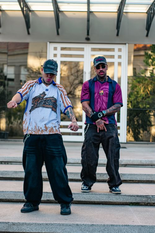 Free Two men in streetwear pose on city steps showcasing urban fashion trends. Stock Photo