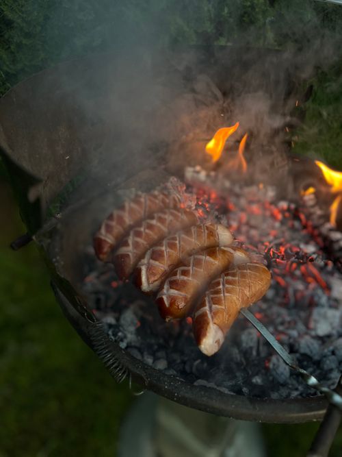 Free Juicy sausages being grilled over an open flame on a barbecue, perfect for a summer cookout. Stock Photo