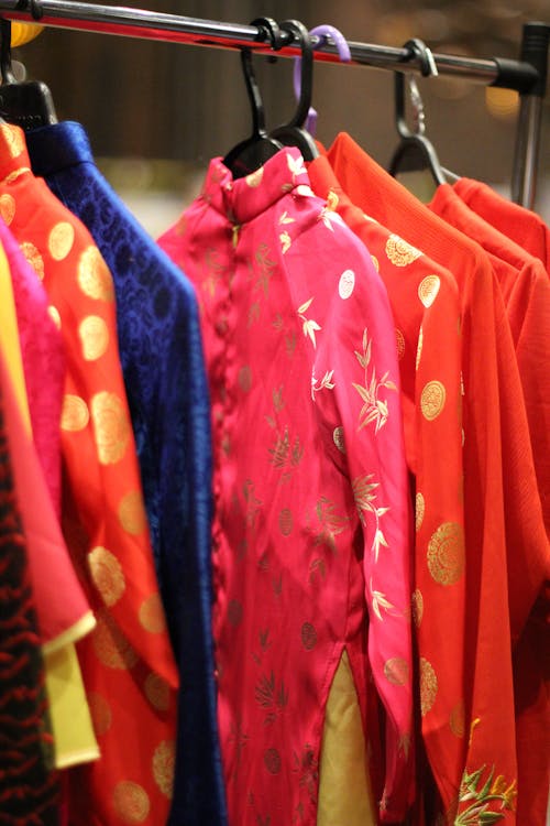 Traditional Japanese clothes of different bright colors with golden ornament hanging on cloth rack