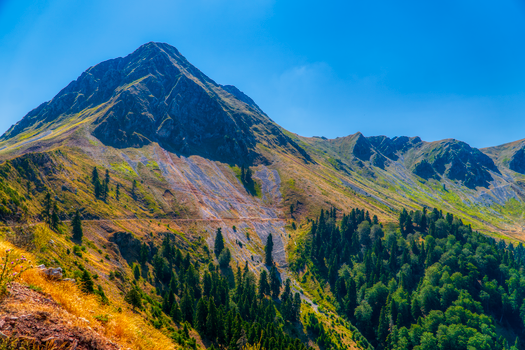 Majestic mountain landscape in Άγραφα, Greece under a clear blue sky, featuring lush greenery and rugged peaks.