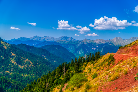 Vibrant mountain view in Ágrafa, Greece with lush forests and striking blue skies.
