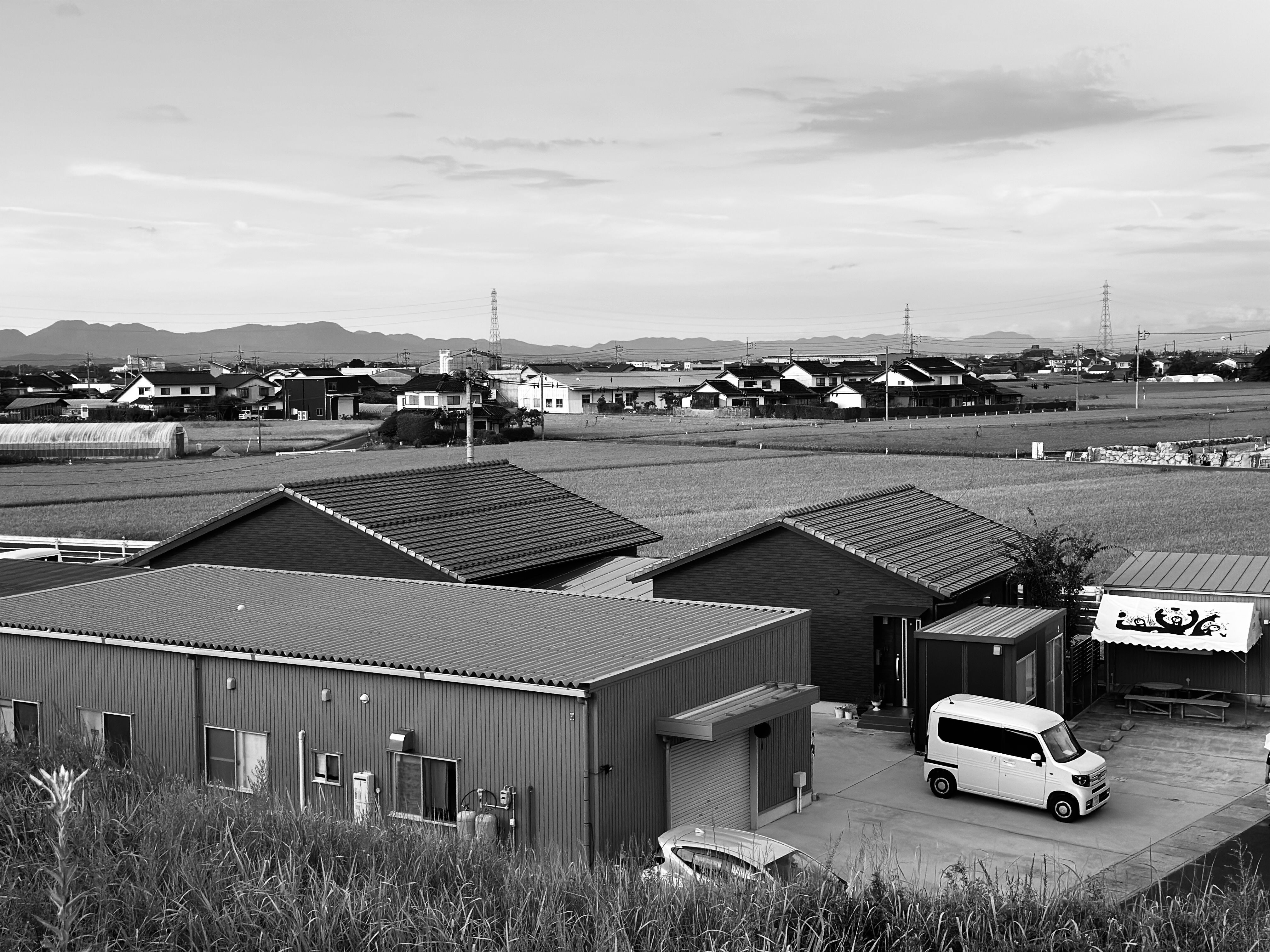 建物や車両が写った、日本の田園風景の白黒写真。