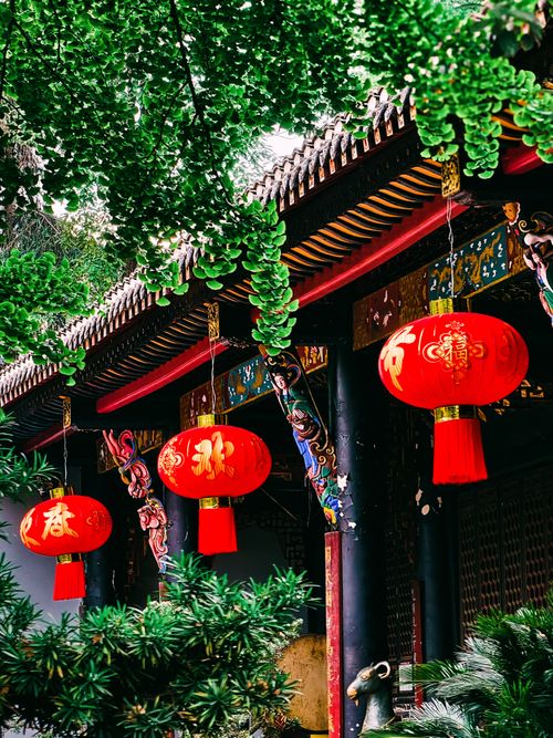 Free Red Chinese lanterns hanging in an ornate outdoor setting with lush greenery. Stock Photo