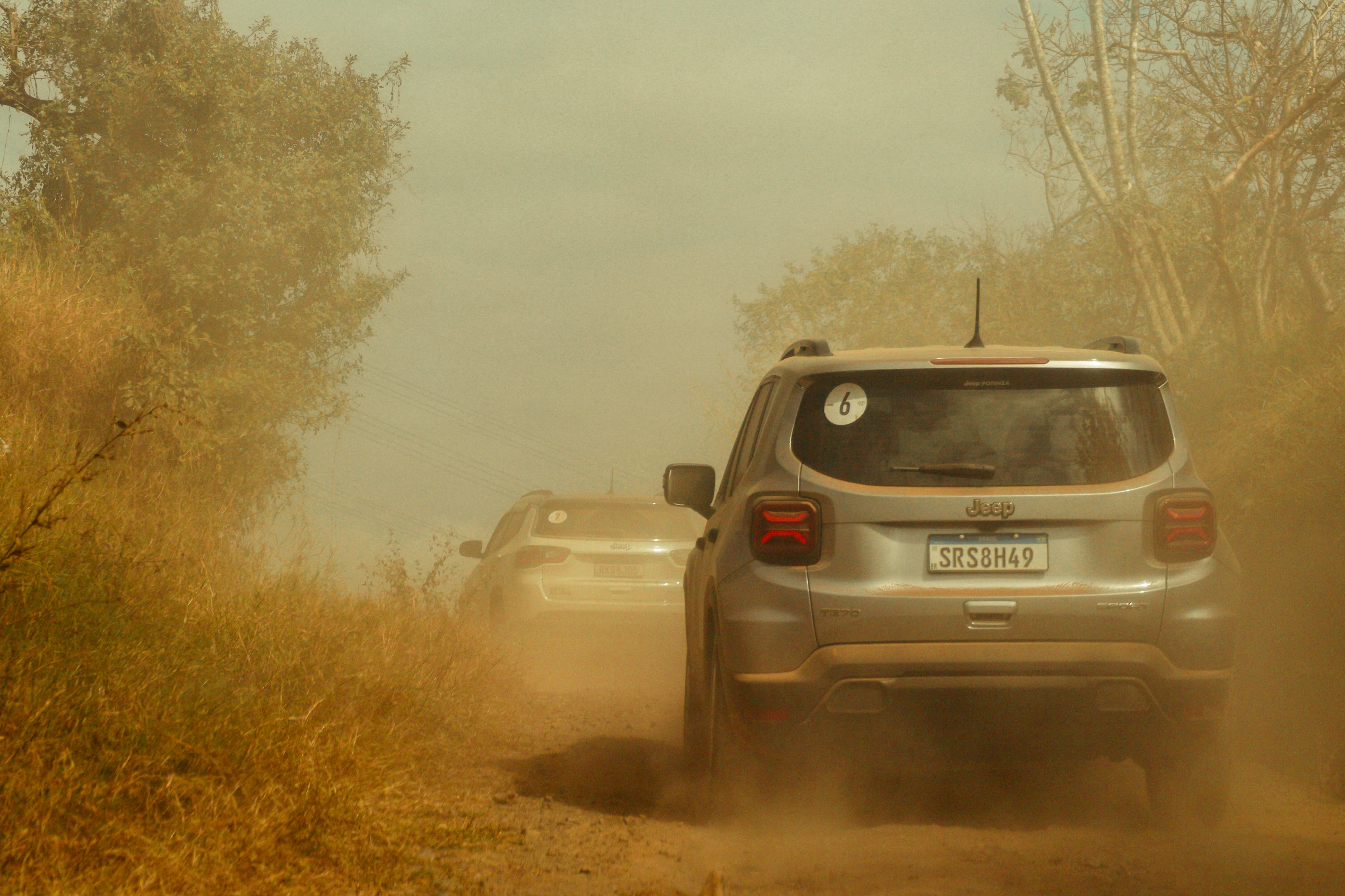 Two SUVs driving along a dusty off-road trail