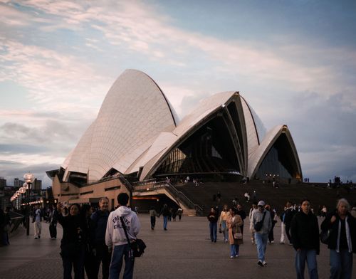 Free A bustling scene at Sydney Opera House during twilight with people walking around. Stock Photo