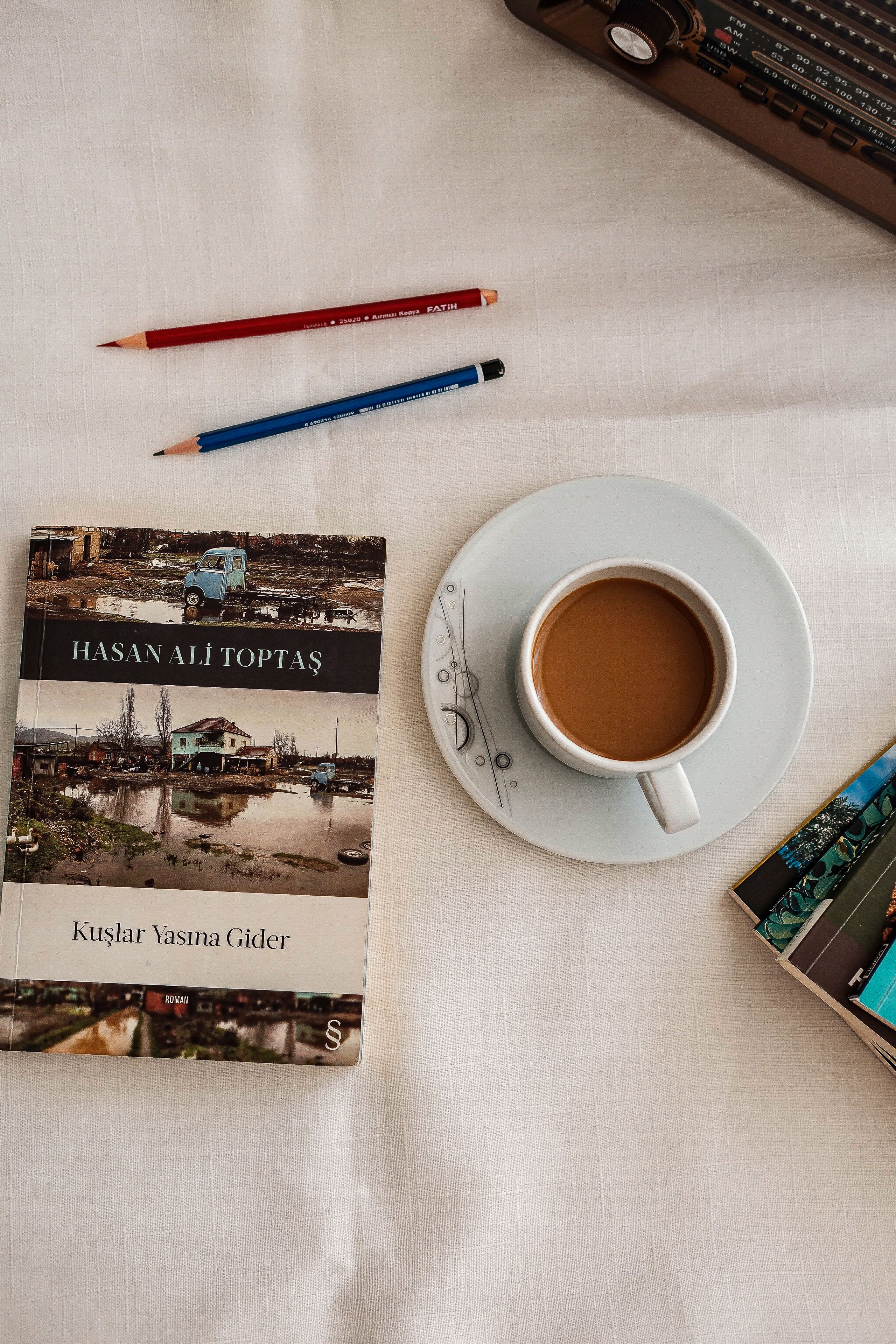 A relaxing setup featuring a book by Hasan Ali Toptaş and a cup of coffee, perfect for a cozy afternoon.