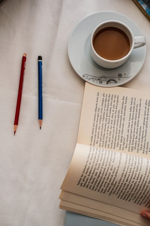 Free A calming scene of a book, coffee cup, and pencils arranged on a table, perfect for relaxation. Stock Photo