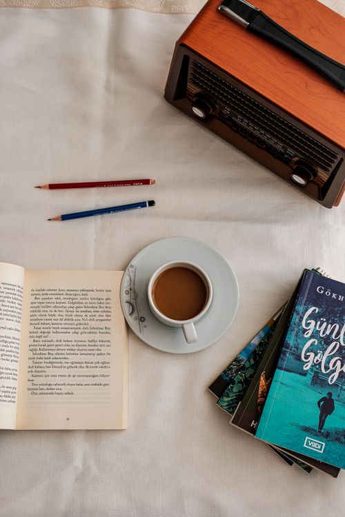 Free Top-down view of an inviting reading space with coffee, books, pencils, and a vintage radio. Stock Photo
