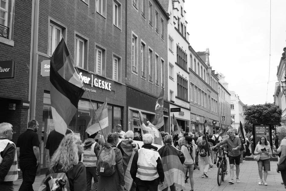 Personas marchando con banderas en una calle de la ciudad durante una protesta diurna.