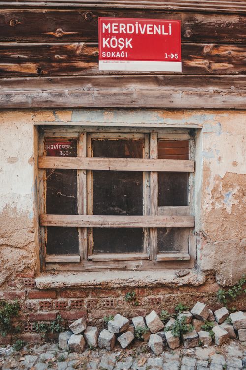 Free A charming rustic window with a Turkish street sign in a worn urban environment. Stock Photo