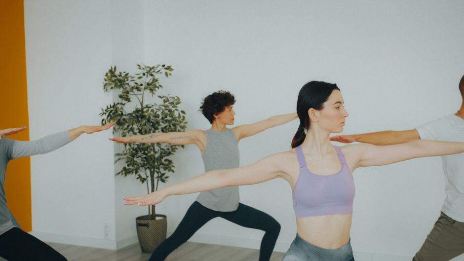 Adults practicing yoga poses in a modern, minimalist studio.