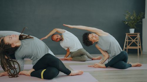 Free A diverse group of adults practicing side stretches during a yoga session in an indoor studio. Stock Photo