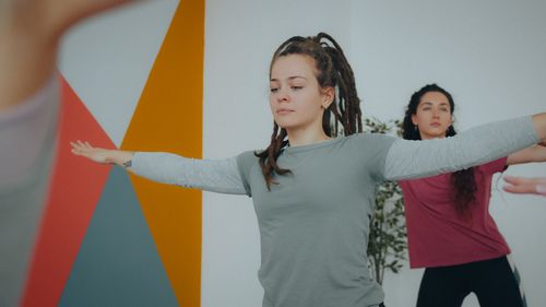Free Two women practicing yoga poses in a modern, indoor studio setting focused on mindfulness. Stock Photo