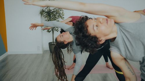 Free A group of adults practicing yoga stretches in a bright indoor setting, promoting health and wellness. Stock Photo