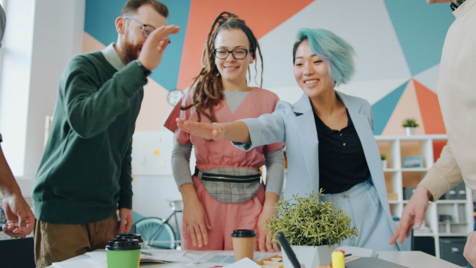 Jóvenes profesionales creativos colaborando alegremente en un espacio de oficina moderno y colorido.