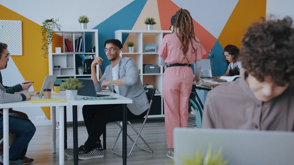 Equipo diverso que trabaja en colaboración en un entorno de oficina elegante y colorido.