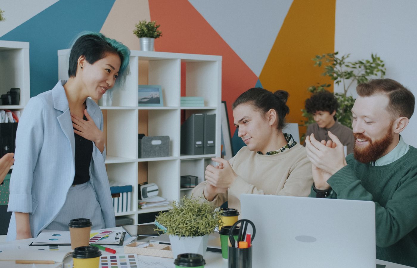 Team members applaud a colleague during a project presentation in a modern office.