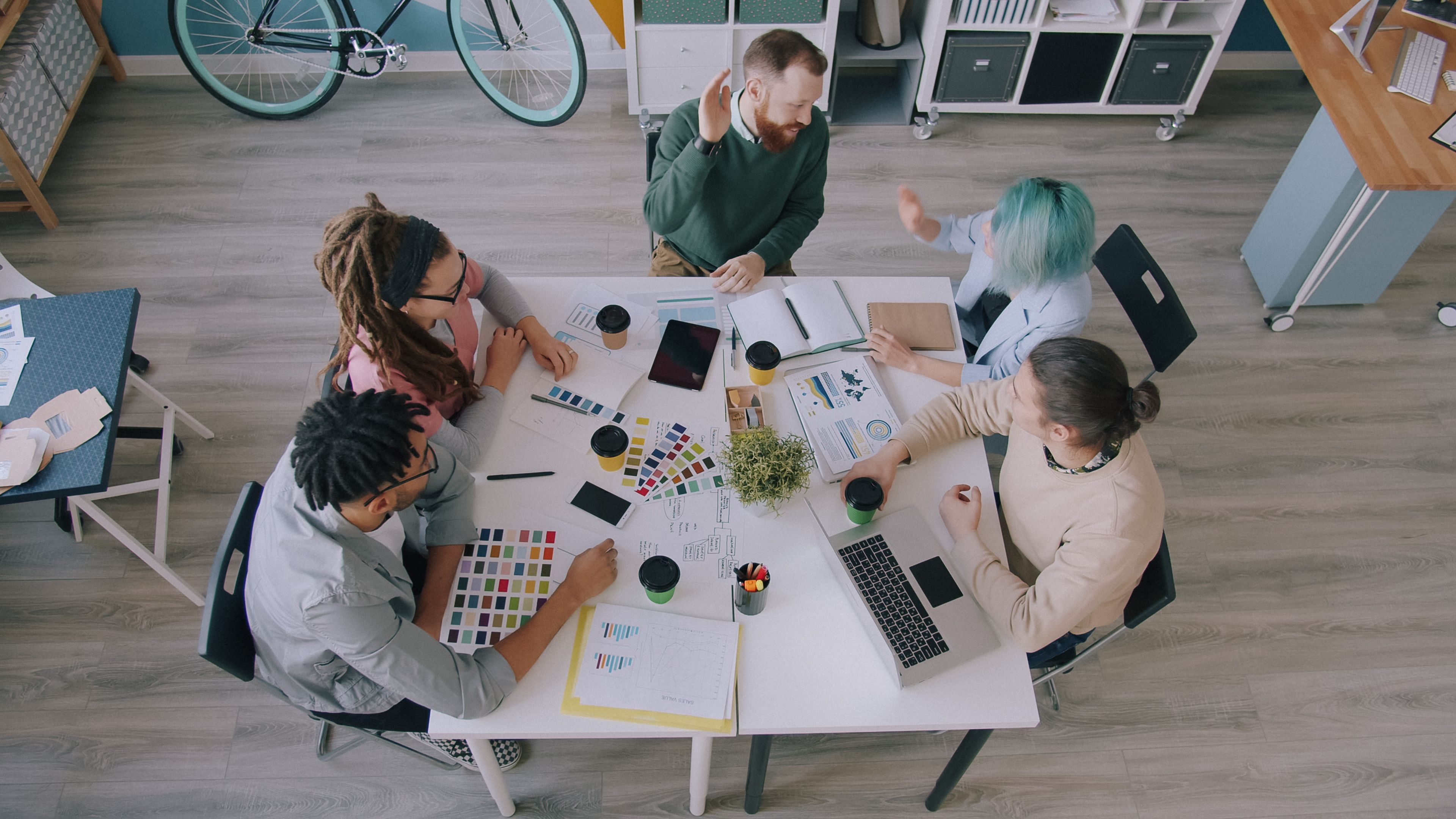 Creative team collaborating at a workspace with digital devices and layout boards