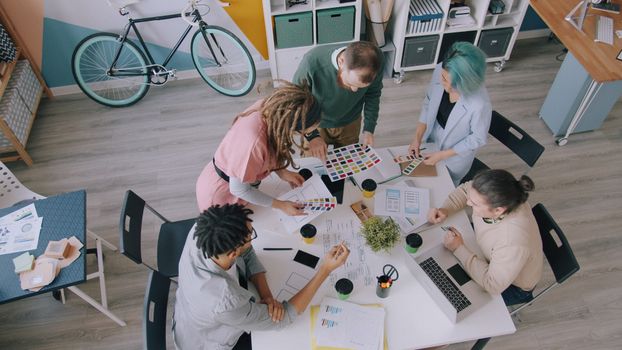 High-angle shot of a diverse team brainstorming in a modern office setting.