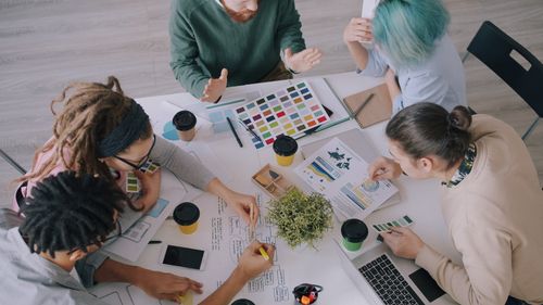 Free Creative team discusses design projects using color swatches and charts in office. Stock Photo