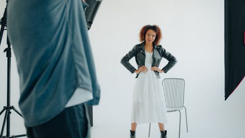Free Studio portrait of a confident woman wearing a white dress and leather jacket during a photoshoot. Stock Photo