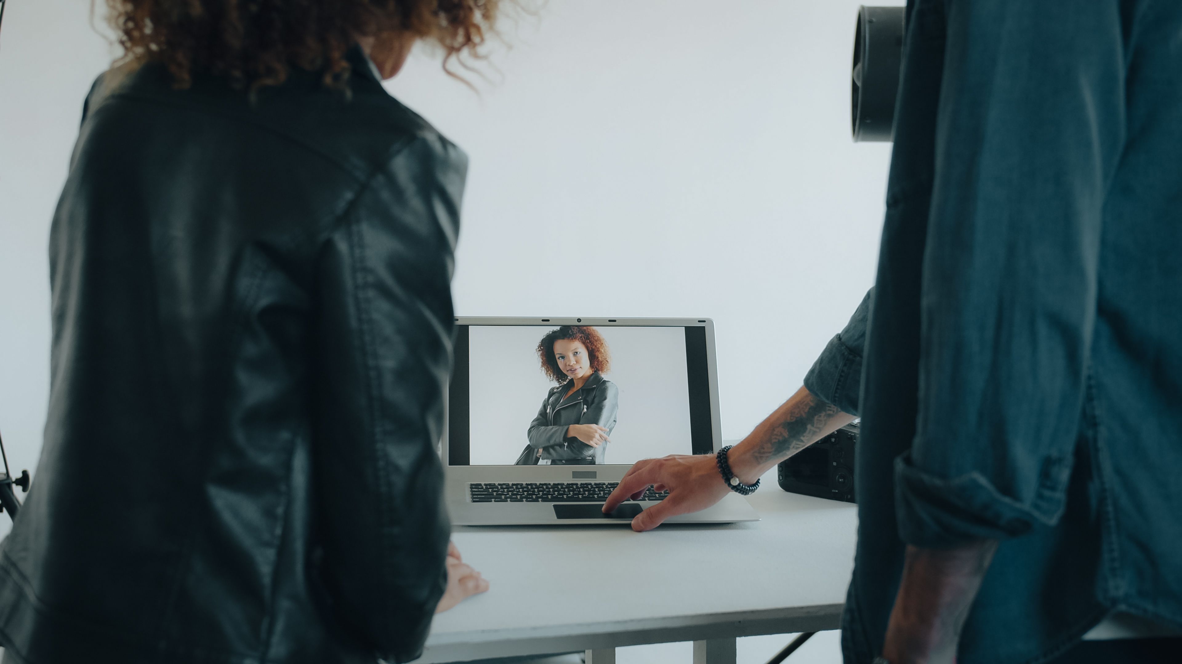 Two people reviewing a portrait on a laptop screen during a photo shoot.