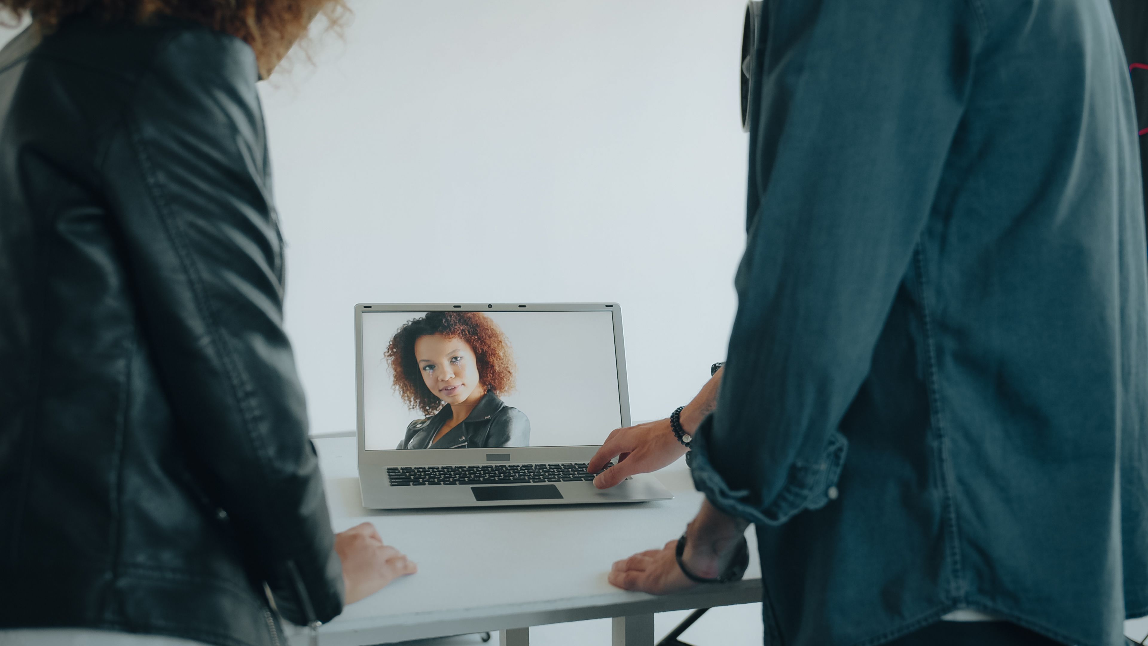 Dos personas ante un ordenador portátil que muestra el rostro de una mujer durante una videollamada