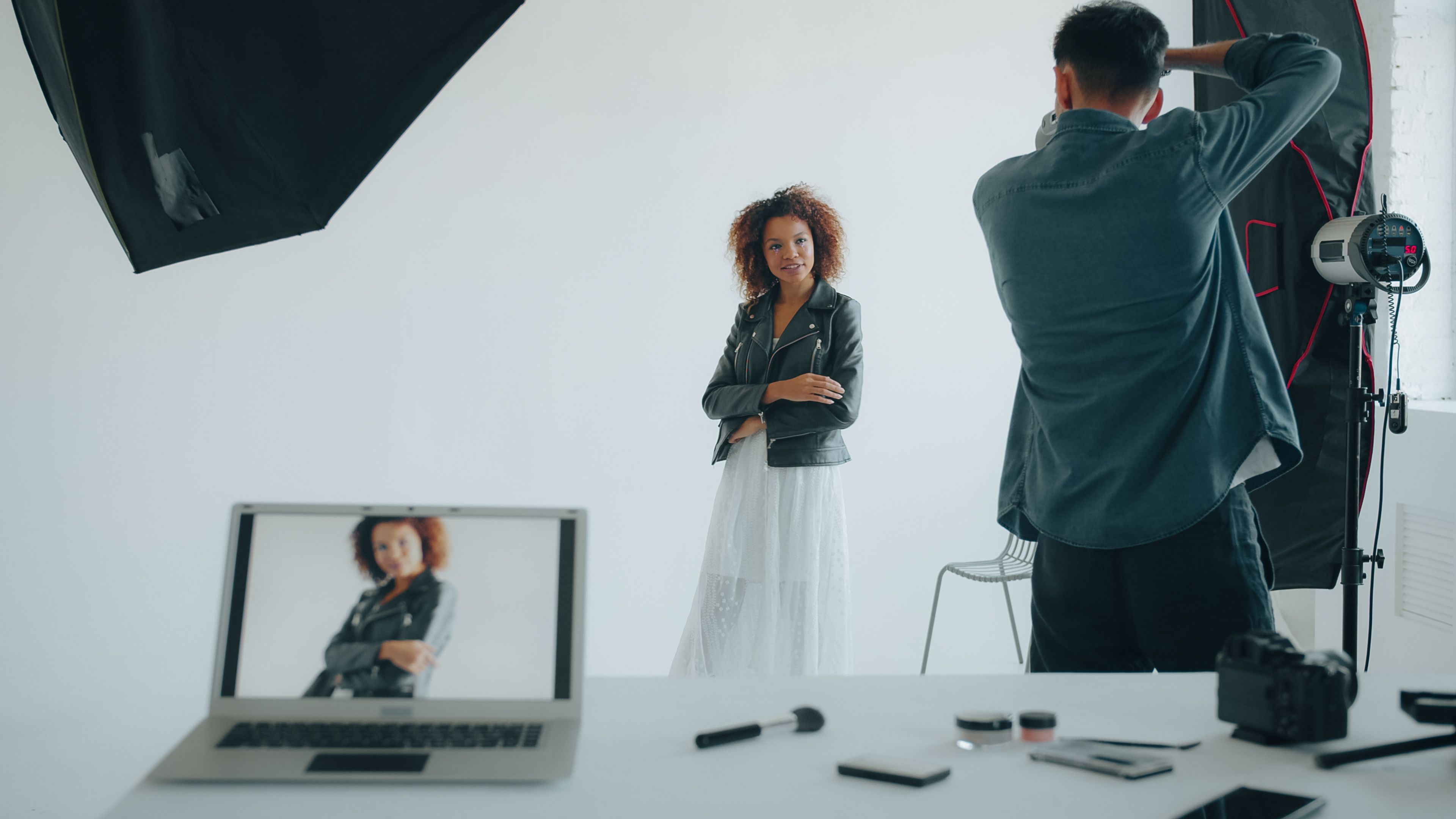 Photographer capturing a stylish woman in a modern studio setup with professional equipment.
