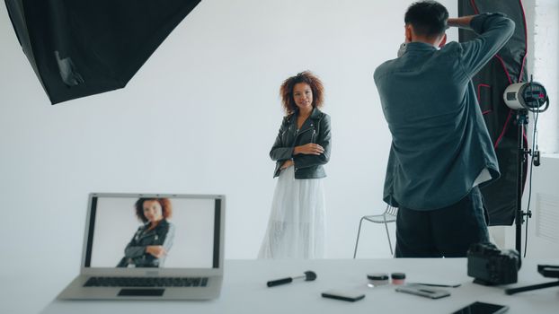 Photographer capturing a stylish woman in a modern studio setup with professional equipment.
