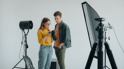 Free Two photographers review camera settings in a professional photo studio environment. Stock Photo